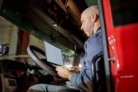 Technician seated in a truck cab working on a laptop