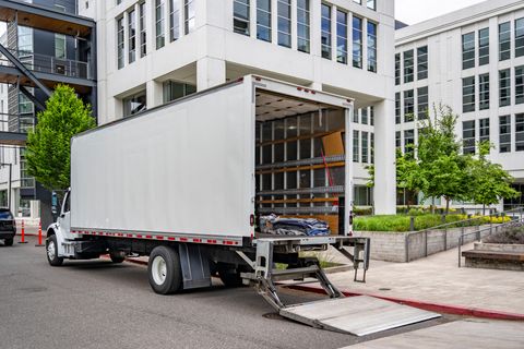 Box truck parked at a curb with its lift gate lowered to the street