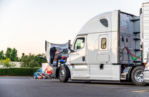 White semi tractor with the hood open at a parking lot