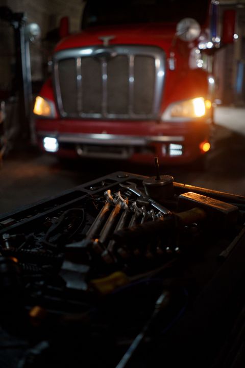 Semi tractor parked in a dark shop bay with a tray of wrenches in the foreground