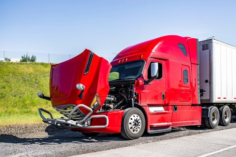 Red semi tractor pulled onto the shoulder with its hood open