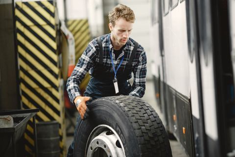 Technician rolling a commercial truck tire across a shop floor