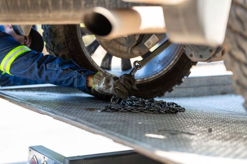 Worker securing a chain at the wheel end of a truck on a trailer deck