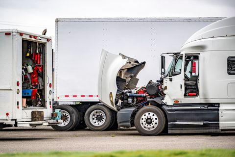 Mobile service truck with its tool doors open parked beside a semi tractor with the hood raised